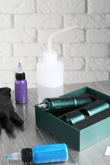 Modern professional tattoo machine and colorful inks on table in salon