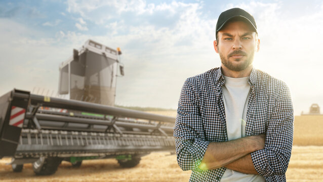 A bearded farmer in a cap and a plaid shirt stands in front of a combine harvester