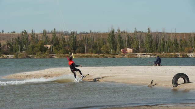 Kiteboarder rides on a kite in sea bay. Freestyle kiter training on pond kiteboarding spot. Kitesurfer enjoying ride. Extreme water sports. Slow motion 120 fps.