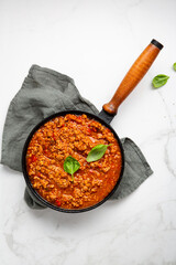 Overhead view of red meat sauce in skillet pan on textile