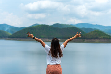 Woman rise her hands up to sky with mountain and water in Chiangmai Thailand for freedom, success and travel concept.