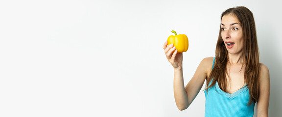 Young woman looking in surprise at yellow paprika isolated on white background. Banner