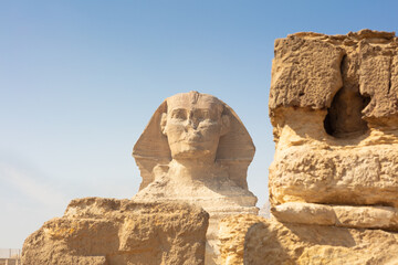 Fototapeta na wymiar Egyptian Great Sphinx full body portrait with head, feet with all pyramids of Menkaure, Khafre, Khufu in background on a clear, blue sky day in Giza, Egypt empty with nobody.
