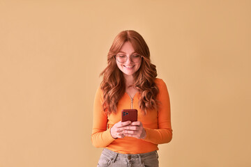   Portrait of a beautiful red-haired woman on a yellow background with a phone.