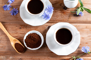 Healthy hot chicory drink in the cup , crushed chicory root in small white bowl and milk in glass jug on a table. Top view