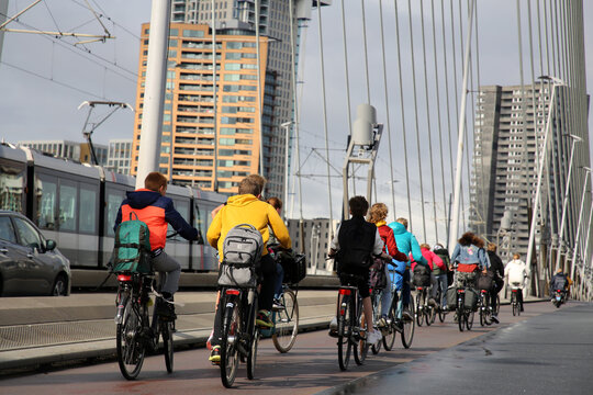Young students riding bike on the Erasmus Bridge over Maas or Meuse River in Rotterdam, NL