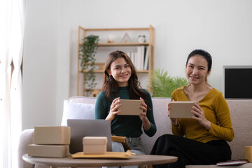 Portrait of Starting small businesses SME owners, two Asian woman check online orders Selling products working with boxs freelance work at home office, sme business online small medium enterprise