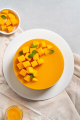 Delicious glazed mango no baked cheese cake with fresh diced mango pulp topping on bright table background.