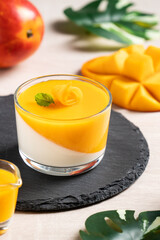 Fototapeta na wymiar Delicious double colored mango panna cotta mousse pudding on wooden table background.