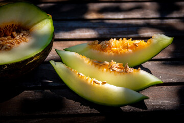 Melon jaune coupé en tranche sur une table en bois dans le jardin ensoleillé