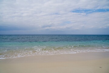 Fototapeta na wymiar The white sands of Nagamahama Beach and the ocean seen from Kurima Island
