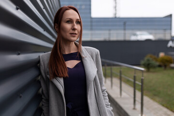 portrait of a successful forty-year-old red-haired businesswoman against the backdrop of the office center