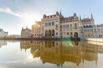 Hungarian Parliament with warm sun in the background and reflection