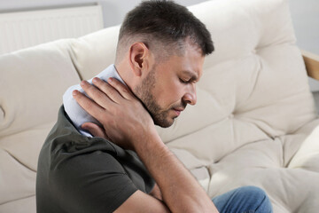 Man using heating pad on sofa at home © New Africa