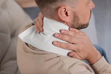 Man using heating pad indoors, closeup view © New Africa