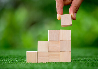 Stacking blank wooden cubes on green background with copy space for input wording and infographic...