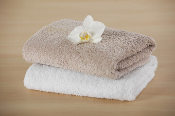 Obraz na płótnie Canvas Soft folded towels with orchid flower on wooden table