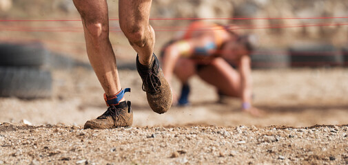 Mud race runners. Crawling,passing under a barbed wire obstacles during extreme obstacle race