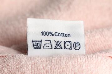 Clothing label on pink fluffy towel, closeup