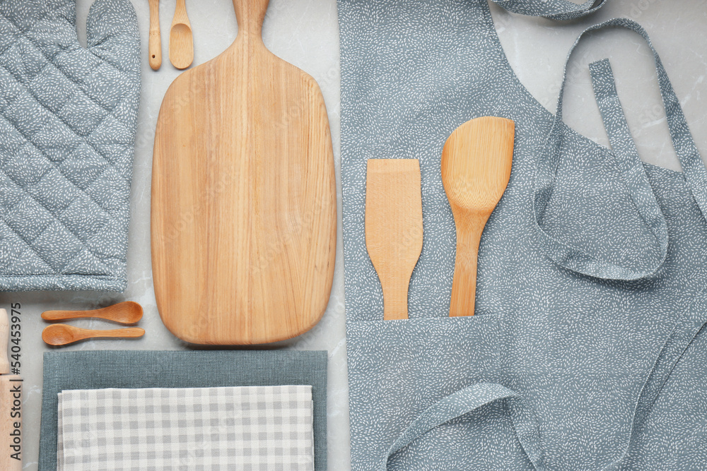 Sticker Kitchen napkins, apron and different utensils on light grey table, flat lay