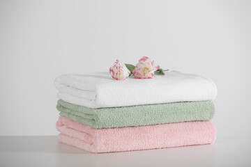 Fototapeta na wymiar Soft folded towels with eustoma flowers on white table