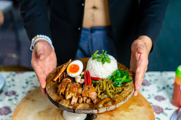 Man hands holding stewed pork leg on plate wood