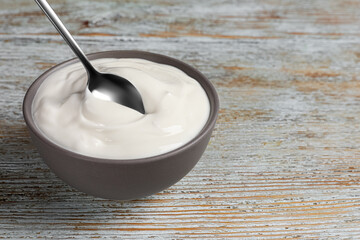 Ceramic bowl with delicious organic yogurt on wooden table, closeup. Space for text
