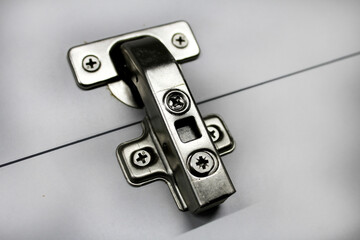 Metal furniture hinge with a door closer as a background image.