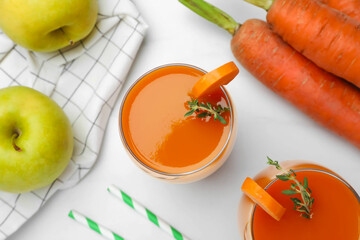 Glass with healthy carrot juice and ingredients on white table, flat lay