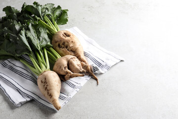 Fresh sugar beets with leaves on light grey table. Space for text