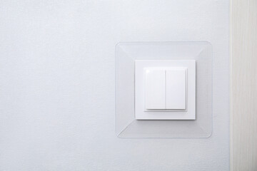 Modern plastic light switch on white wall, space for text