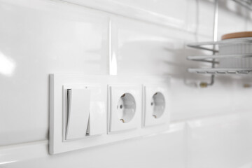Light switch and power sockets on white wall indoors