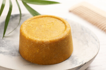 Dish with solid shampoo bar on table, closeup
