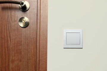 Modern plastic light switch on white wall indoors