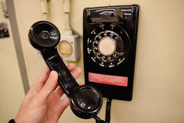 A cold war era bunker phone with wires with a red text informing you that you're being listened to and it's not safe for classified information.