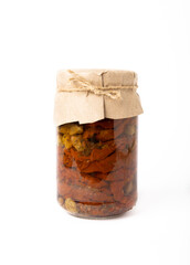 Dried tomatoes in a jar with spices and herbs isolated on a white background. Autumn seasonal pickled vegetables. Autumn home canning products. Side view.