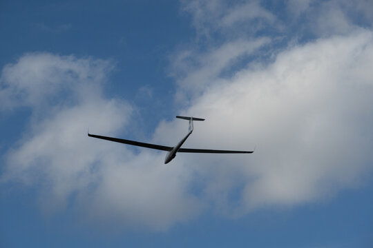 a glider or sailplane flying over an airfield.