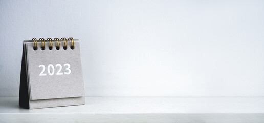 Merry christmas and happy new year 2023 banner. 2023 business year numbers on modern small grey desk calendar cover on white background with copy space, minimal style. Ready to start a new goals.