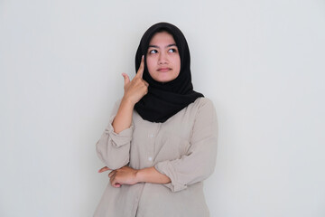 Fototapeta premium Asian young girl wearing hijab looking above while thinking about something