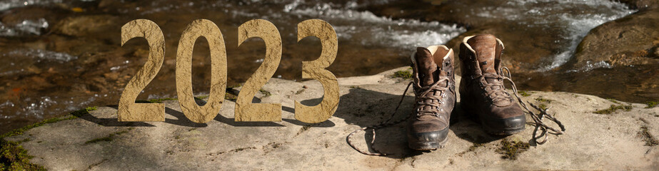 Rocky 2023 on a mountain riverside with a pair of trekking shoes ready for adventure. Active new year concept.