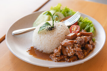 Stir fired teriyaki chicken with streamed rice on wooden background