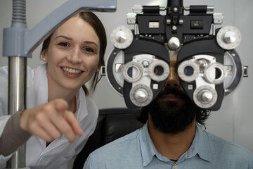 An eye doctor examines a male patient in a clinic with modern equipment.