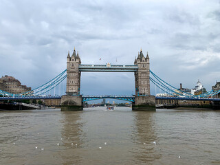 Fototapeta na wymiar The historic Tower Bridge stands like a huge rock in the surf of the London Thames, a ship passes under it, while at the same moment thousands of people can cross the river with the help of the bridge