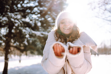Happy young woman in snowy winter park. Cold weather. Holidays, rest, travel concept.