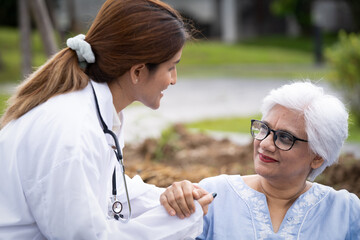 Beautiful young nurse with smiling elderly woman happy in the park lawn