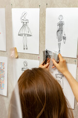 Woman fashion designer is working on creating sketches of dresses. Design and tailoring. Seamstress in the studio.