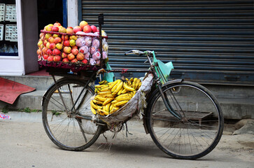 Fototapeta na wymiar Bicycle cart hawker of nepali man vendor stop on road sale variety fruits and food to nepalese people and foreign travelers buy eat drink on street bazaar market at thamel old town in Kathmandu, Nepal