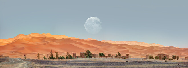 General view of the Merzouga hotels district with full moon - Merzouga, Sahara, Morocco 