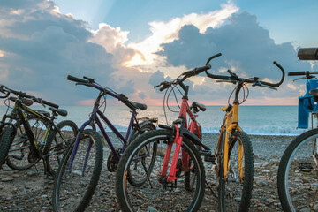 Fototapeta na wymiar The row of bikes on the beach wit blue cloudy sky and sea background