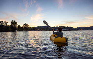 Adventurous Woman Kayaking on an Inflatable Kayak in the Pacific Ocean. Sunset Sky. Port Moody,...